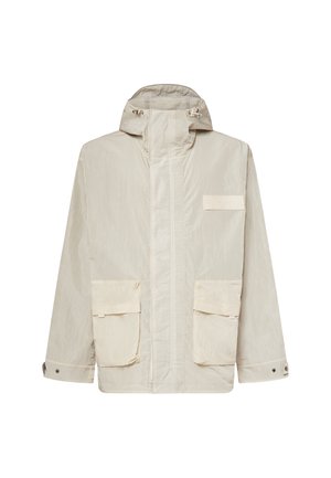 Giacca beige chiaro con cappuccio, zip frontale, due grandi tasche con patta, polsini regolabili e una piccola toppa rettangolare sul petto.