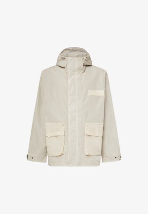 Lyse beige hættejakke med forlynlås, to store klaplommer, justerbare manchetter og et lille rektangulært mærke på brystet.