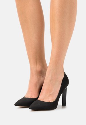 Escarpins en suède noir à bout pointu avec une finition texturée. Dotés d'un talon épais pour la stabilité et d'un design classique.