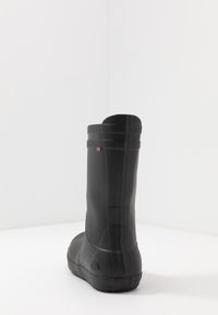 Svarta vattentäta stövlar med en texturerad yta, rund tå, låg klack och en liten röd, vit och bl å accent på sidan.