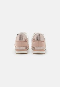 Baskets de sport rose vif avec des accents métalliques, dotées d'une tige en daim texturé et en cuir lisse, d'une languette à l'arrière et d'une semelle blanche contrastante.