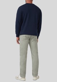 Sweatshirt bleu marine à manches longues, associé à un pantalon droit gris clair. Baskets blanches avec des accents subtils présentant une semelle texturée.
