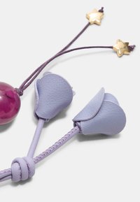 Lilla lædertilbehør med blomsterformede ender, fastgjort til en flettr snor, med en skinnende pink dekorativ perle og guld-stjerne hardware.