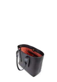 Zwarte leren tote bag met twee handvatten, een oranje interieur en een binnenzak met rits. Beschikt over een gladde textuur en minimale hardware.