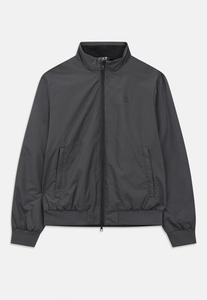 Gray lightweight jacket with a zip front, high collar, elastic cuffs, and hem; features side pockets and minimal branding.