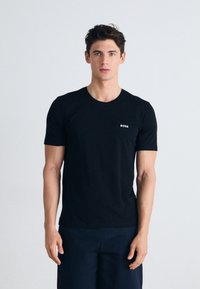 Schwarzes Baumwoll-T-Shirt mit kurzen Ärmeln und Rundhalsausschnitt; verfügt über ein kleines weißes "BOSS"-Logo auf der linken Brust.