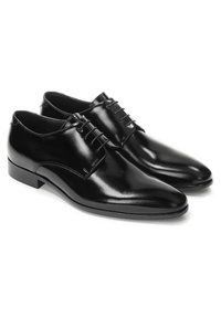 Chaussures habillées en cuir noir avec une finition brillante, à bout arrondi et cinq œillets pour les lacets. Design simple avec un petit talon.