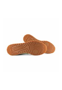 Scarpe con suola in gomma, dotate di una suola arancione con texture, caratterizzate da un logo circolare e vari modelli di battistrada, viste dal basso.