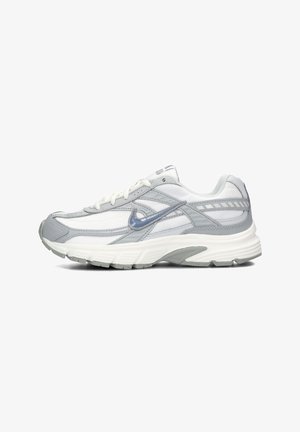 Zapatilla de running Nike con una mezcla de material de malla gris y blanco, con una suela texturizada y detalles reflectantes en los laterales.