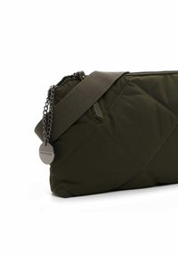 Olive green quilted bag with a textured surface, featuring a zipper closure, adjustable fabric strap, and a chain accent with branding tag.