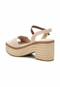 Sandalia de plataforma beige con una cinta ancha, punta abierta y una correa marrón en el tobillo. Presenta un tacón de yute trenzado texturizado para mayor altura.