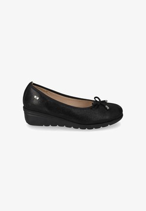 Ballerina nera con zeppa, punta arrotondata, dettaglio con fiocco e suola imbottita su sfondo bianco.