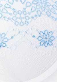 Valkoinen rintaliivi, jossa on tekstiili, jossa on sininen kukkakuosi. Muotoilussa on koholla olevia elementtejä ja sileitä reunoja, jotka korostavat sen muotoa.