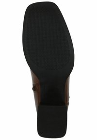 Suela de zapato de cuero marrón con una parte inferior de goma negra, que presenta un patrón de agarre texturizado y una forma aerodinámica.