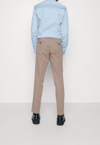 Ljust blå skjorta med knappar parat med khakibyxor. Byxorna har bakfickor och en skräddarsydd passform, kompletterat med svarta skor.