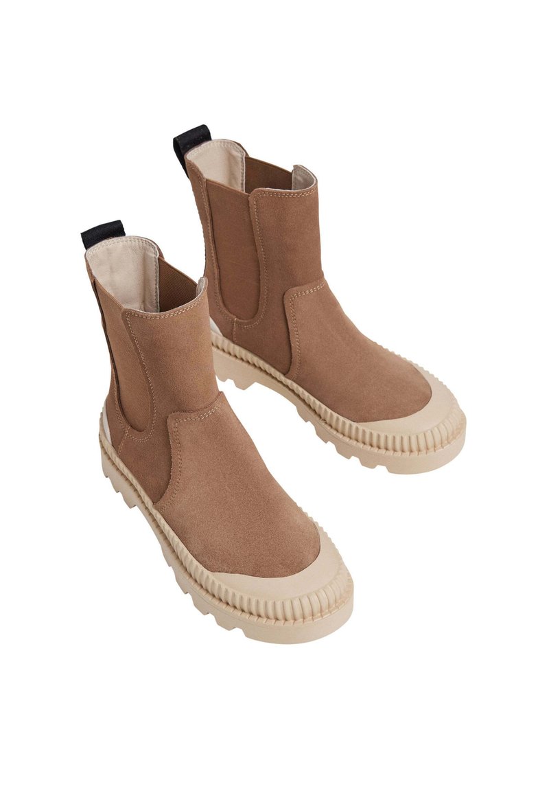 Brązowe zamszowe botki za kostkę z elastycznymi bokami, teksturowane beżowe gumowe podeszwy i czarne pętle z tyłu. Okrągły czubek.