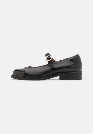 Black patent leather Mary Jane shoe with a rounded toe, single strap featuring a circular metallic buckle, and low block heel.