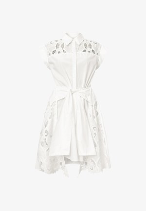 Valkoinen mekko, jossa on napitettu etuosa, hihattomat hihat ja pitsiyksityiskohtia yläosassa ja hameessa. Sidottu vyötärölle vastaavalla nauhalla.