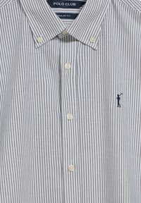 Randig skjorta med knappar i vitt och marinblått, med klassisk krage, vanlig passform och en liten logobrodering på bröstet.