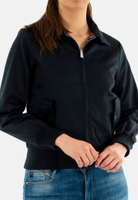 Zwarte bomberjack van gladde stof, met een rits aan de voorkant, twee zijzakken, geribbelde manchetten en een kleurrijke voering van de kraag.