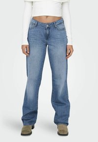 Jeans de mezclilla de corte ancho en azul claro, con diseño estándar de cinco bolsillos, cierre de botón y un ligero desvanecimiento en los muslos y las rodillas.
