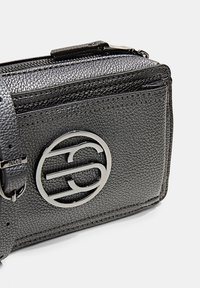 Černá kožená crossbody taška s texturovaným povrchem, stříbrným kruhovým logem, zipovým uzávěrem a nastavitelným popruhem.