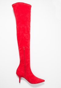 Botte cuissarde en daim rouge avec un bout pointu et un talon stiletto de 10 cm. Elle possède une fermeture éclair latérale et une texture lisse.