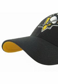 Casquette de baseball noire avec un dessous de visière jaune, arborant un logo brodé d'un pingouin et de os croisés sur l'avant.