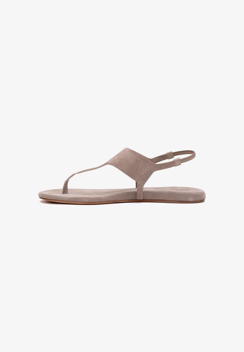 Sandale plate beige avec un entre-doigt, une large bride au milieu du pied, et une bride arrière élastique sur une semelle fine.