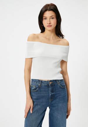 Hvid ribbet off-the-shoulder top med en tætsiddende design. Kombineret med højtaljede blå denim jeans med klassisk fem-lommes stil.