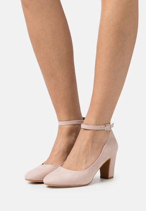 Rosa Wildleder-Ankle-Strap-Absatzschuhe mit runder Spitze und Blockabsatz, ausgestattet mit einem zarten Schnallenverschluss am Knöchel.