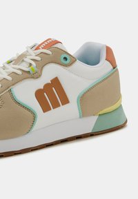 Baskets beiges et blanches avec une finition texturée, dotées d'un logo marron, d'accents turquoise et d'un design de semelle multicolore.