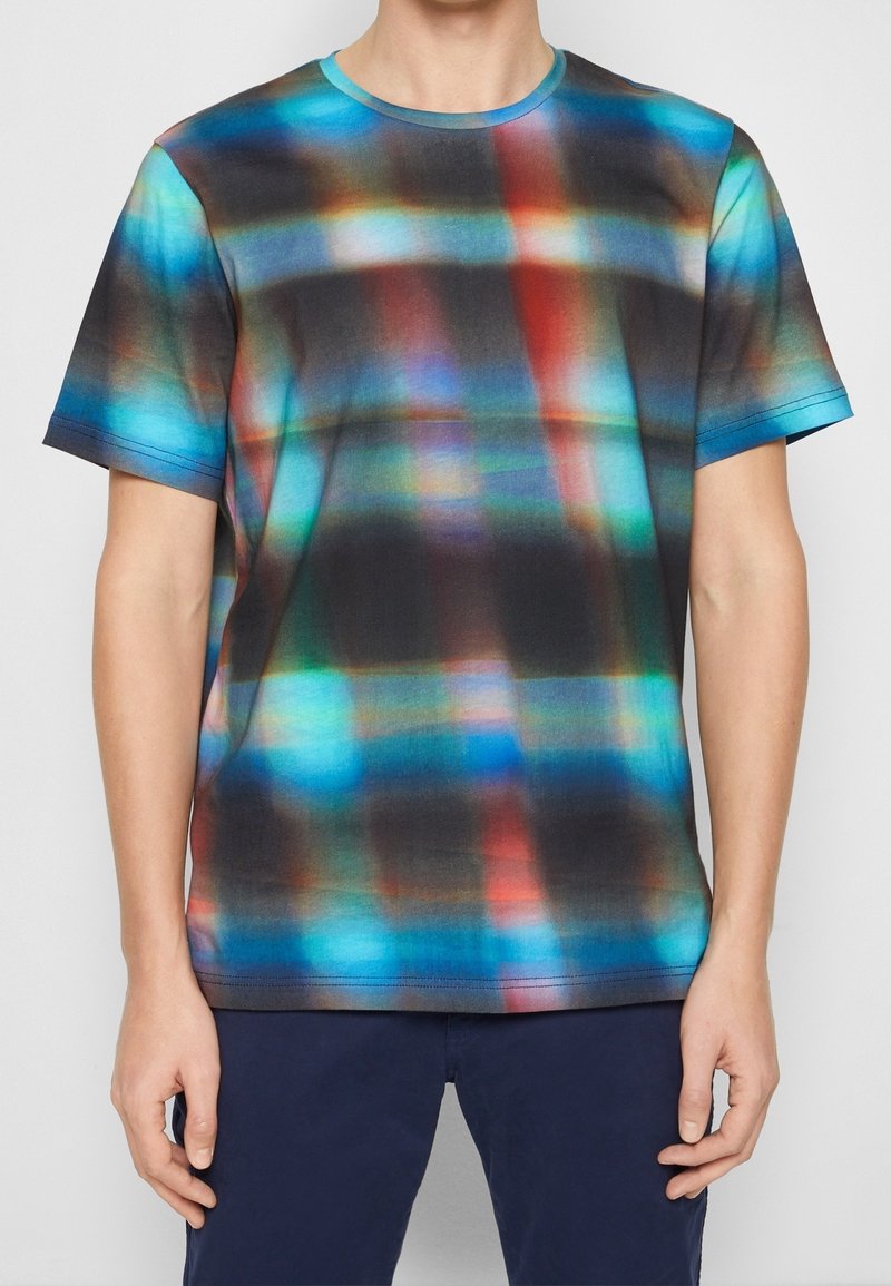 T-shirt à manches courtes présentant un motif à carreaux multicolores en bleu, rouge et noir, avec un col rond et une texture de tissu lisse.