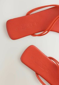 Sandale plate roșii, cu un finisaj neted și mat, și curele subțiri. Prezintă un logo embosat și dimensiuni. Talpa texturată pentru o aderență bună.