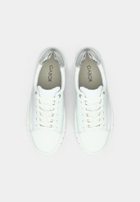 Άσπρα δερμάτινα αθλητικά παπούτσια με ασημένιες λεπτομέρειες, με στρογγυλή μύτη, μπροστινό δέσιμο με κορδόνια και λεία υφή. Το όνομα της μάρκας 'Gabor' εμφανίζεται εσωτερικά.