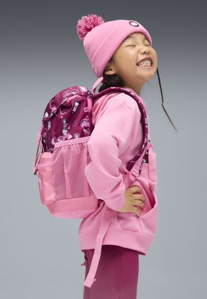 Lyserød rygsæk med et mønstret hovedrum, sidenetlomme og lyserøde accenter. Barnet bærer matchende lyserødt tøj og en hue.