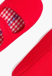 Czerwone płaskie baletki z płótna z okrągłym noskiem, z wycięciami i podszewką w białą i czerwoną kratkę.