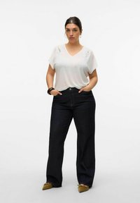 White short-sleeve V-neck t-shirt with lace detail on shoulders, paired with dark blue wide-leg jeans and brown pointed flats.