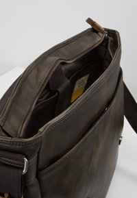 Braune Leder-Umhängetasche mit einer strukturierten Oberfläche, ausgestattet mit einem Reißverschluss oben, mehreren Innenfächern und einem verstellbaren Tragegurt.