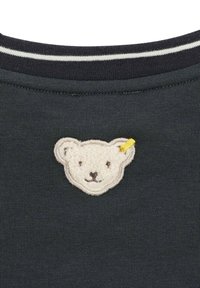 Camisa gris oscuro con un aplique de oso blanco texturizado, con acentos de costura negra y un detalle amarillo en la oreja. Cuello a rayas.