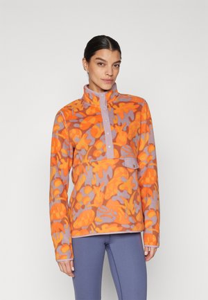 Fliisist pullover oranžis ja lavendlis, millel on abstraktsed lillemustrid, kõrge krae, nööpide rivistus ja esikoti detail. Pehme tekstuur.