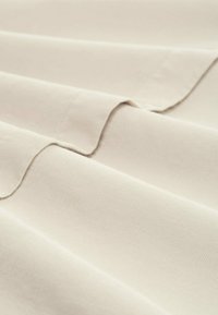 Tessuto avorio con una trama a costine, caratterizzato da pieghe morbide e fluide e una superficie stampata pulita ed uniforme. Leggero e si drappeggia delicatamente.