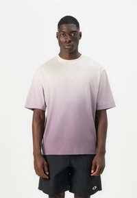 T-Shirt mit kurzen Ärmeln in einem Farbverlauf von hellem Creme zu Lavendel. Weicher Stoff, Rundhalsausschnitt, mit kleinem Logodetail auf der Brust.