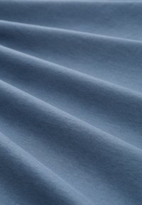 Lichtblauwe stof met een gladde textuur, met subtiele vouwen en kreuken, geschikt voor kleding of bekledingstoepassingen.