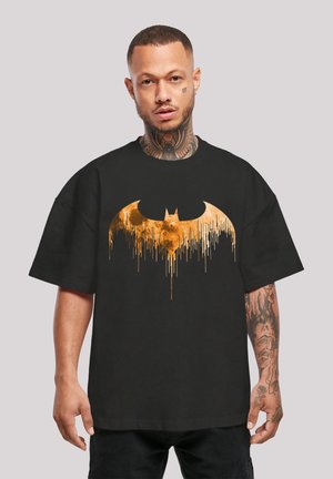 Fekete, oversized póló nagy, csöpögő arany Batman logóval. Rövid ujjak, laza szabás és puha anyagból készült.