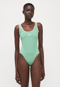 Maillot de bain une pièce vert menthe avec un contraste de bord blanc et le logo 'Hilfiger' sur le devant. Matériau élégant et design minimaliste.