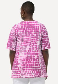 Top de manga corta con base blanca y un atrevido estampado geométrico en rosa. Corte holgado con cuello redondo y textura de tela suave.