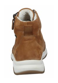 Bruine leren enkelboot met een witte zool, zachte voering en decoratieve stiksels. Heeft een ritssluiting en een lus aan de hak.