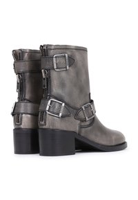 Botas de tobillo metálico gris con dos cremalleras laterales, correas decorativas y acentos de metal plateado. Tacón ancho negro para mayor estabilidad.
