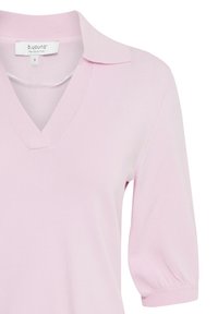 Pull rose clair à manches courtes avec col en V, poignets côtelés et une étiquette portant la mention "b.young The Collection" taille small.
